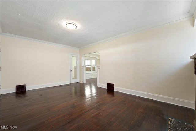 spare room with baseboards, ornamental molding, dark wood-type flooring, and visible vents