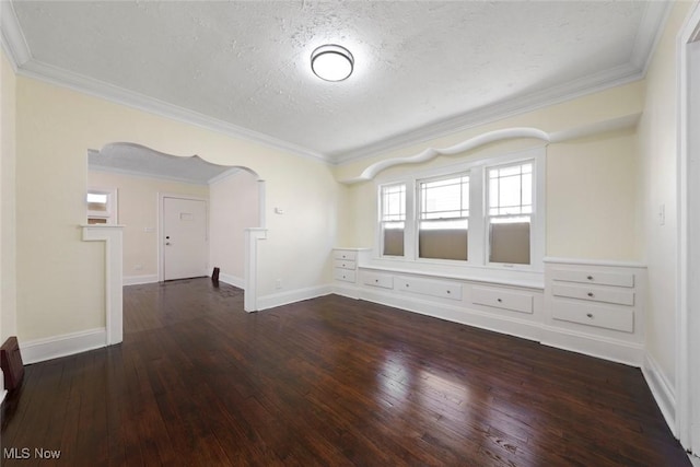 spare room featuring arched walkways, a textured ceiling, baseboards, crown molding, and hardwood / wood-style floors