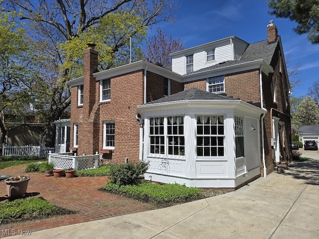 view of side of home featuring a chimney and brick siding