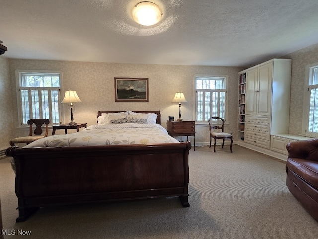 bedroom with carpet floors, a textured ceiling, wallpapered walls, and baseboards
