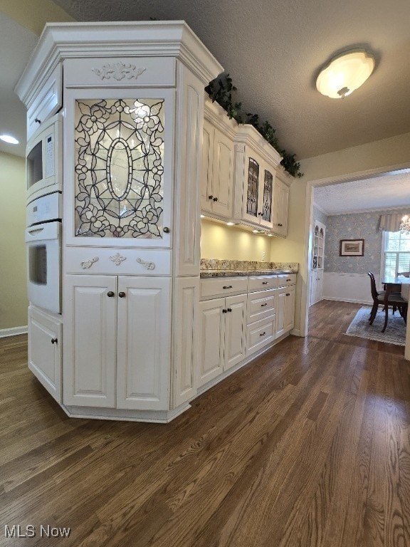 kitchen featuring baseboards, dark wood-style flooring, and white appliances