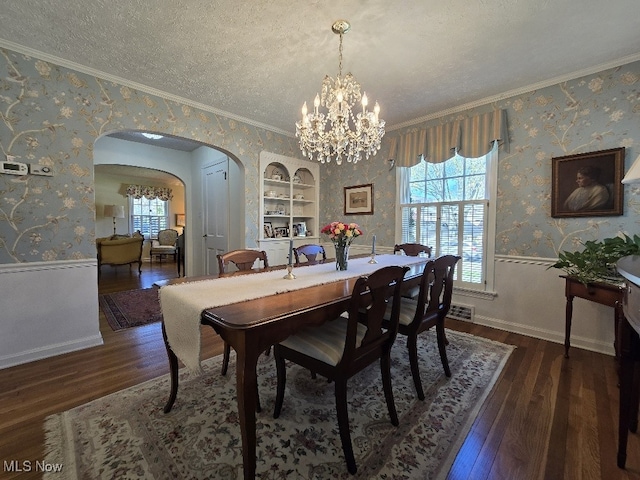 dining room with arched walkways, wallpapered walls, and a wealth of natural light