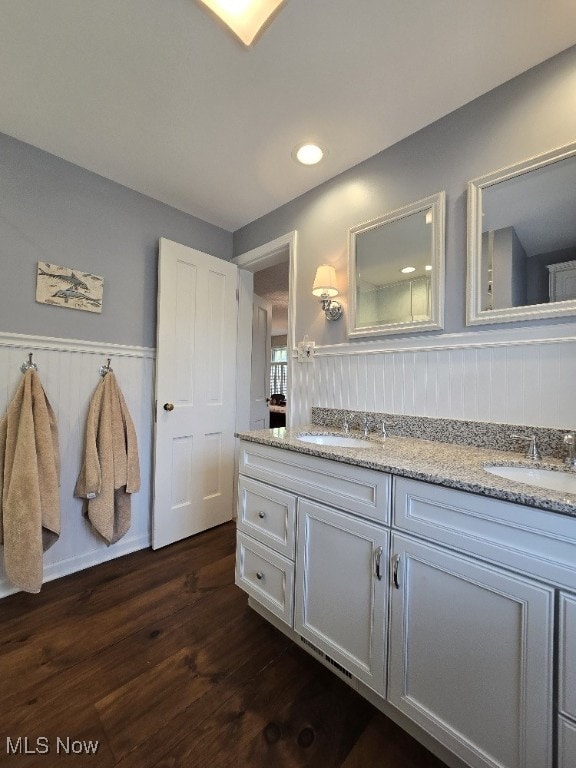 bathroom with wood finished floors, a sink, and a wainscoted wall