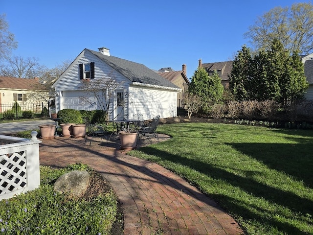 exterior space featuring a garage, a lawn, a chimney, and fence