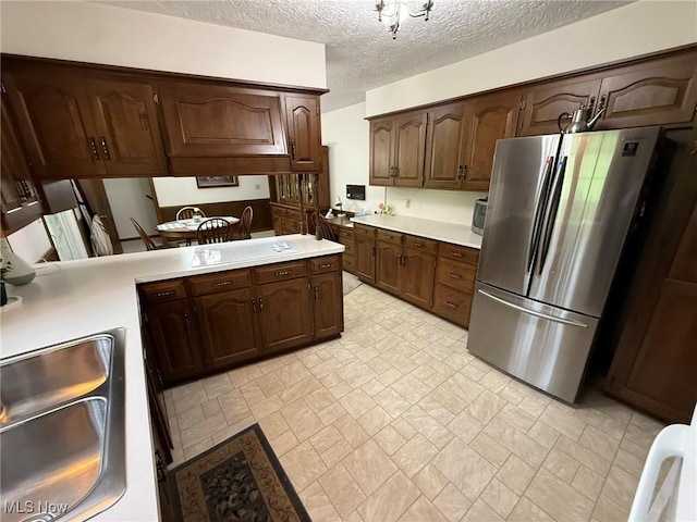 2476 Willow Brook Dr NW, Dover, OH 44622 - kitchen featuring a textured ceiling, a sink, freestanding refrigerator, dark brown cabinetry, and light countertops