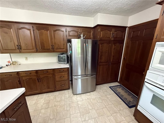 2476 Willow Brook Dr NW, Dover, OH 44622 - kitchen with oven, a textured ceiling, light countertops, and freestanding refrigerator