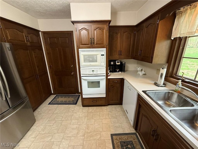 2476 Willow Brook Dr NW, Dover, OH 44622 - kitchen with a sink, a textured ceiling, white appliances, stone finish flooring, and light countertops