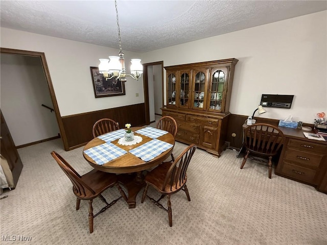 2476 Willow Brook Dr NW, Dover, OH 44622 - dining space featuring a wainscoted wall, wood walls, light carpet, a textured ceiling, and a notable chandelier