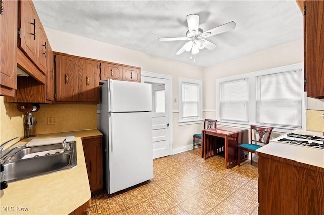 kitchen with light floors, light countertops, a ceiling fan, a sink, and freestanding refrigerator