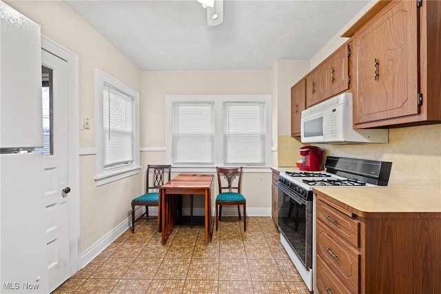 kitchen with brown cabinetry, white appliances, light floors, light countertops, and baseboards