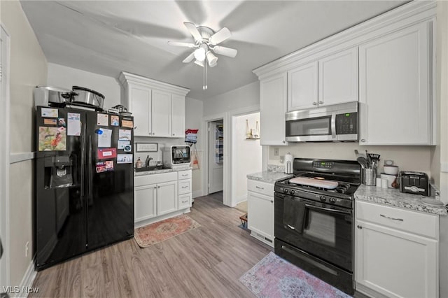 kitchen with ceiling fan, light wood-style floors, baseboards, black appliances, and white cabinetry