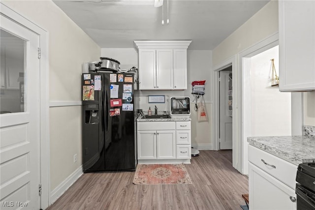 kitchen featuring light countertops, baseboards, black appliances, light wood-style flooring, and white cabinetry