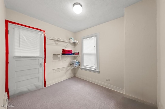 interior space featuring a textured ceiling, carpet flooring, and baseboards