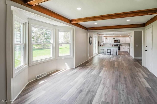 unfurnished living room with beamed ceiling, wood finished floors, visible vents, and recessed lighting