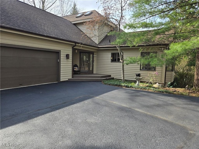 view of front of home featuring a garage, a shingled roof, and driveway