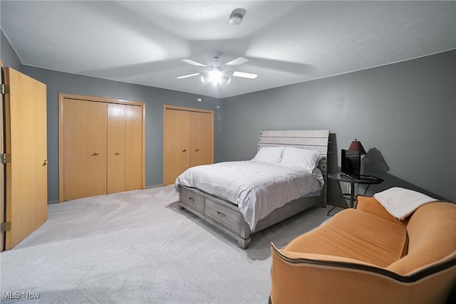 bedroom with ceiling fan, multiple closets, and carpet