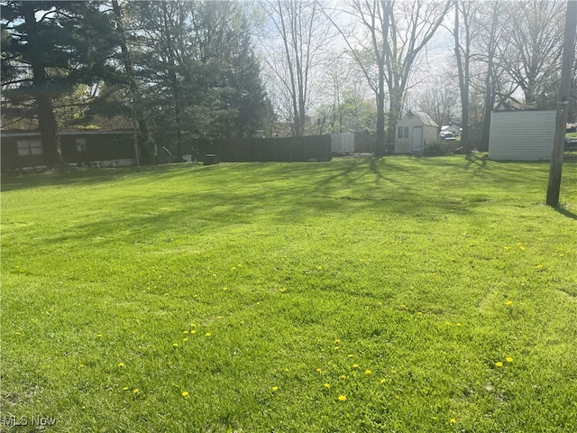 view of yard featuring fence, an outbuilding, and a storage shed