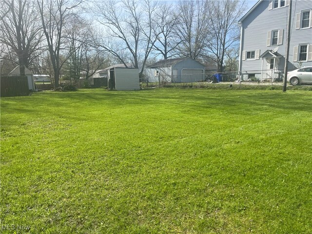 view of yard with fence, an outdoor structure, and a shed