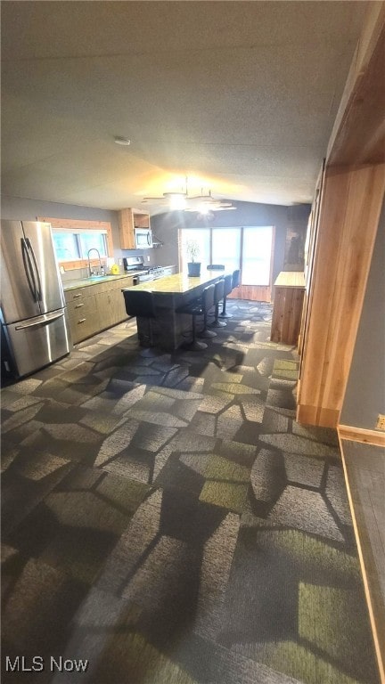 kitchen featuring appliances with stainless steel finishes, a sink, light countertops, and dark carpet