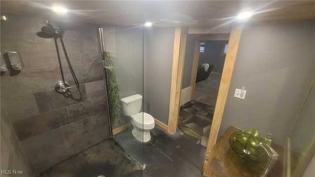 bathroom featuring a tile shower and toilet