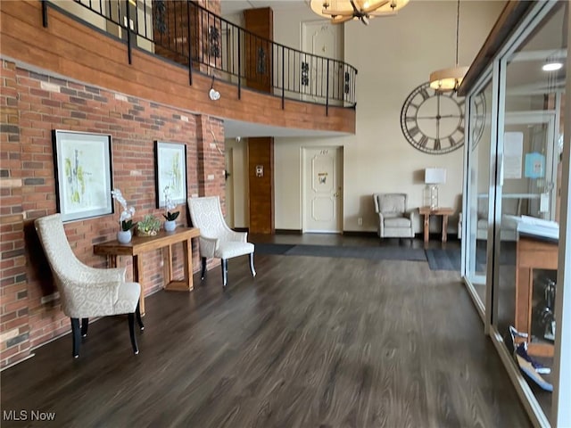 interior space featuring wood finished floors, a high ceiling, baseboards, and brick wall