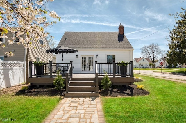rear view of property with a chimney, a wooden deck, a yard, and french doors