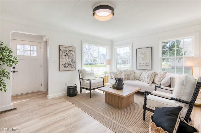 living area with light wood-type flooring, visible vents, and baseboards