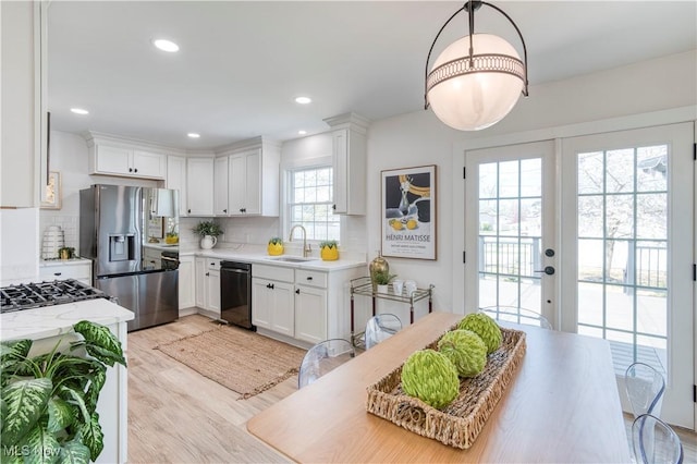 kitchen featuring white cabinets, stainless steel fridge, tasteful backsplash, light wood-style floors, and dishwasher