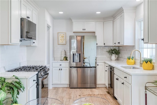 kitchen featuring white cabinets, backsplash, stainless steel appliances, and a sink