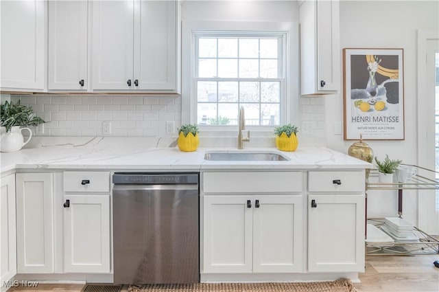 kitchen with stainless steel dishwasher, backsplash, a sink, and white cabinetry