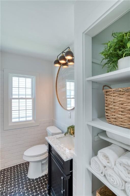 bathroom with toilet, vanity, and wainscoting