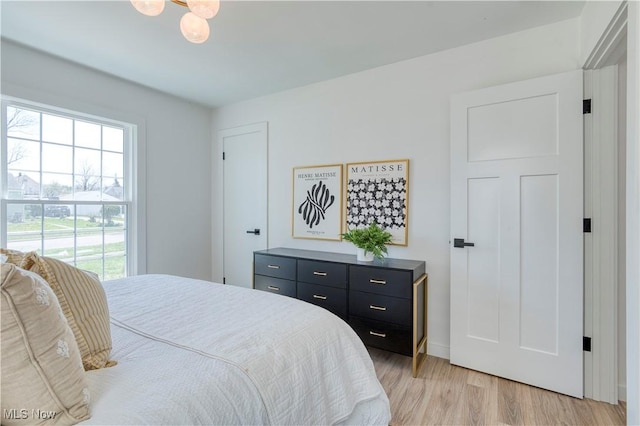 bedroom featuring light wood finished floors and baseboards