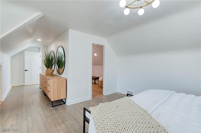 bedroom with light wood-style floors, lofted ceiling, visible vents, and baseboards