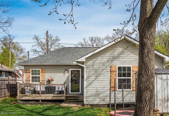 back of property featuring a wooden deck, a shingled roof, and fence