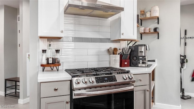 kitchen featuring stainless steel range with gas cooktop, baseboards, tasteful backsplash, and wall chimney range hood