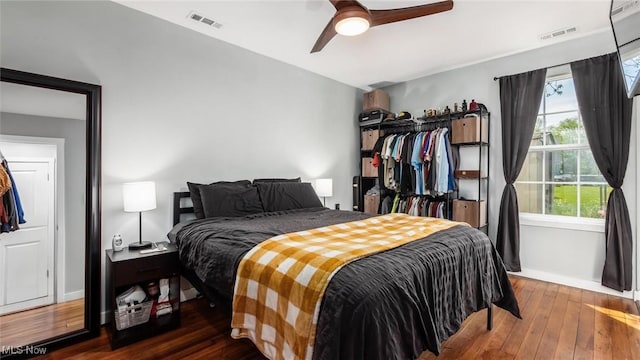 bedroom with wood-type flooring, visible vents, baseboards, and ceiling fan