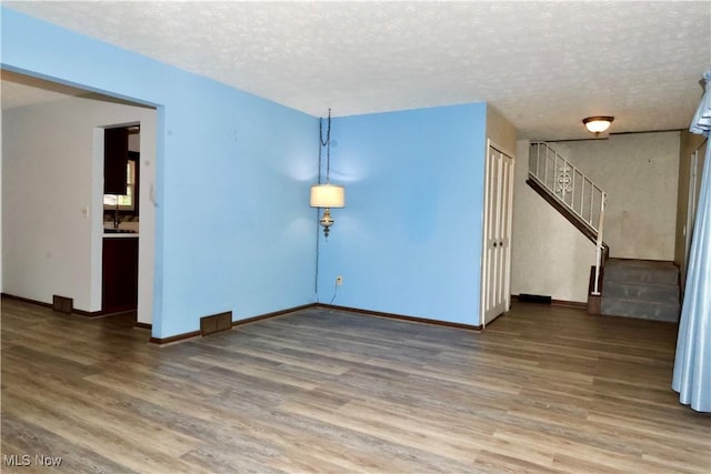 4479 Azalea Ln, North Olmsted, OH 44070 - unfurnished living room featuring baseboards, wood finished floors, a textured ceiling, and stairs