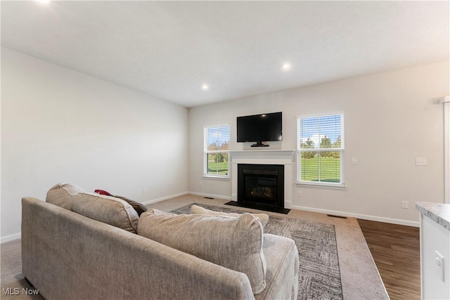 living area featuring wood finished floors, a fireplace with flush hearth, baseboards, visible vents, and recessed lighting