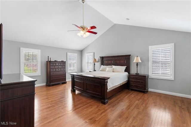 bedroom with lofted ceiling, light wood finished floors, baseboards, and a ceiling fan