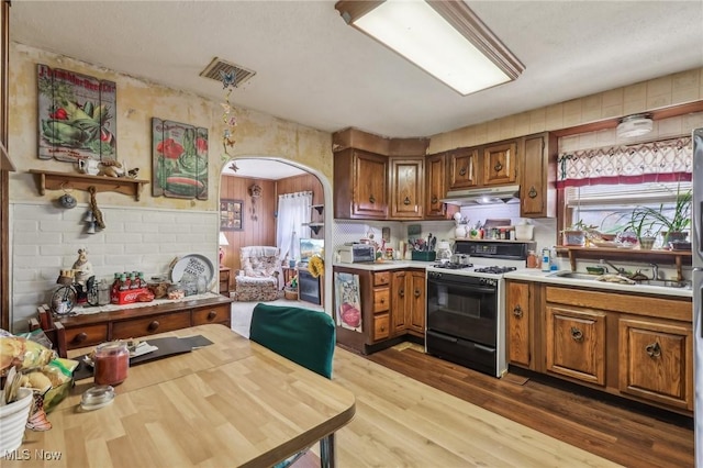 944 Bey Rd, Akron, OH 44312 - kitchen featuring gas range, under cabinet range hood, brown cabinets, and arched walkways