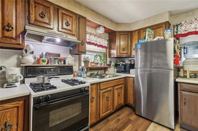 944 Bey Rd, Akron, OH 44312 - kitchen with black appliances, under cabinet range hood, brown cabinetry, light countertops, and dark wood-type flooring