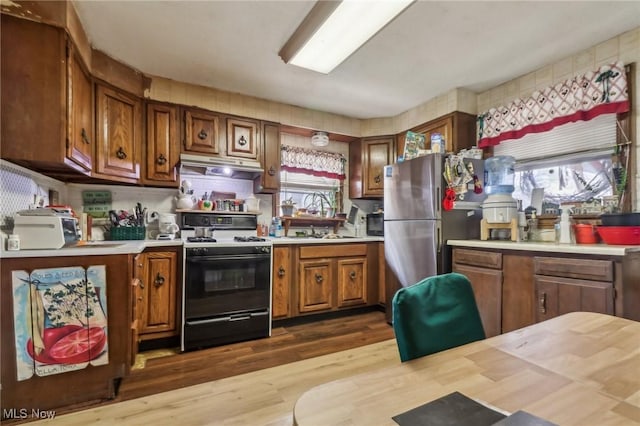 944 Bey Rd, Akron, OH 44312 - kitchen with gas range, under cabinet range hood, light countertops, and brown cabinetry