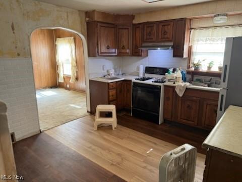 944 Bey Rd, Akron, OH 44312 - kitchen with under cabinet range hood, gas stove, light countertops, light wood-style flooring, and freestanding refrigerator