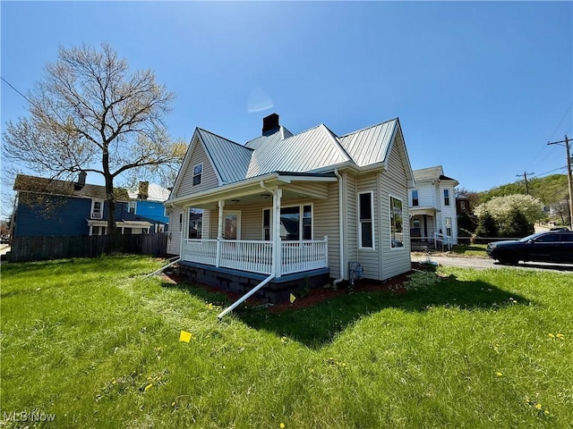 exterior space featuring a chimney, a lawn, fence, a porch, and metal roof