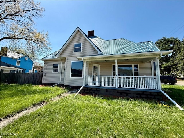 rear view of house with a lawn, a porch, a chimney, and metal roof