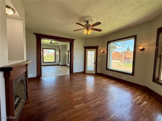 609 Main St, Toronto, OH 43964 - unfurnished living room featuring a textured ceiling, dark wood-style flooring, a ceiling fan, a fireplace, and baseboards