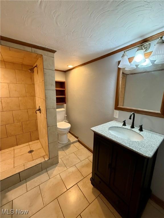 full bathroom with toilet, vanity, ornamental molding, and a tile shower
