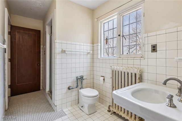 full bathroom featuring tile patterned floors, a stall shower, tile walls, radiator, and toilet