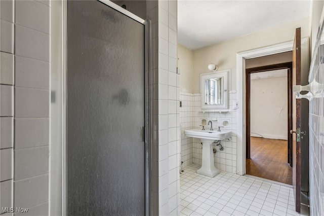 full bath featuring tile walls, tile patterned floors, a stall shower, and wainscoting