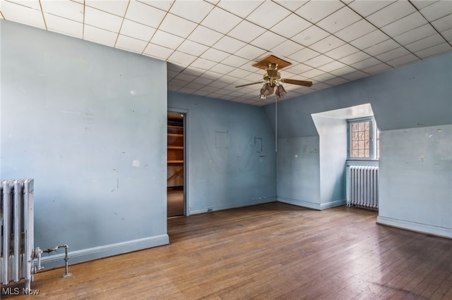 interior space with wood-type flooring, a ceiling fan, and radiator